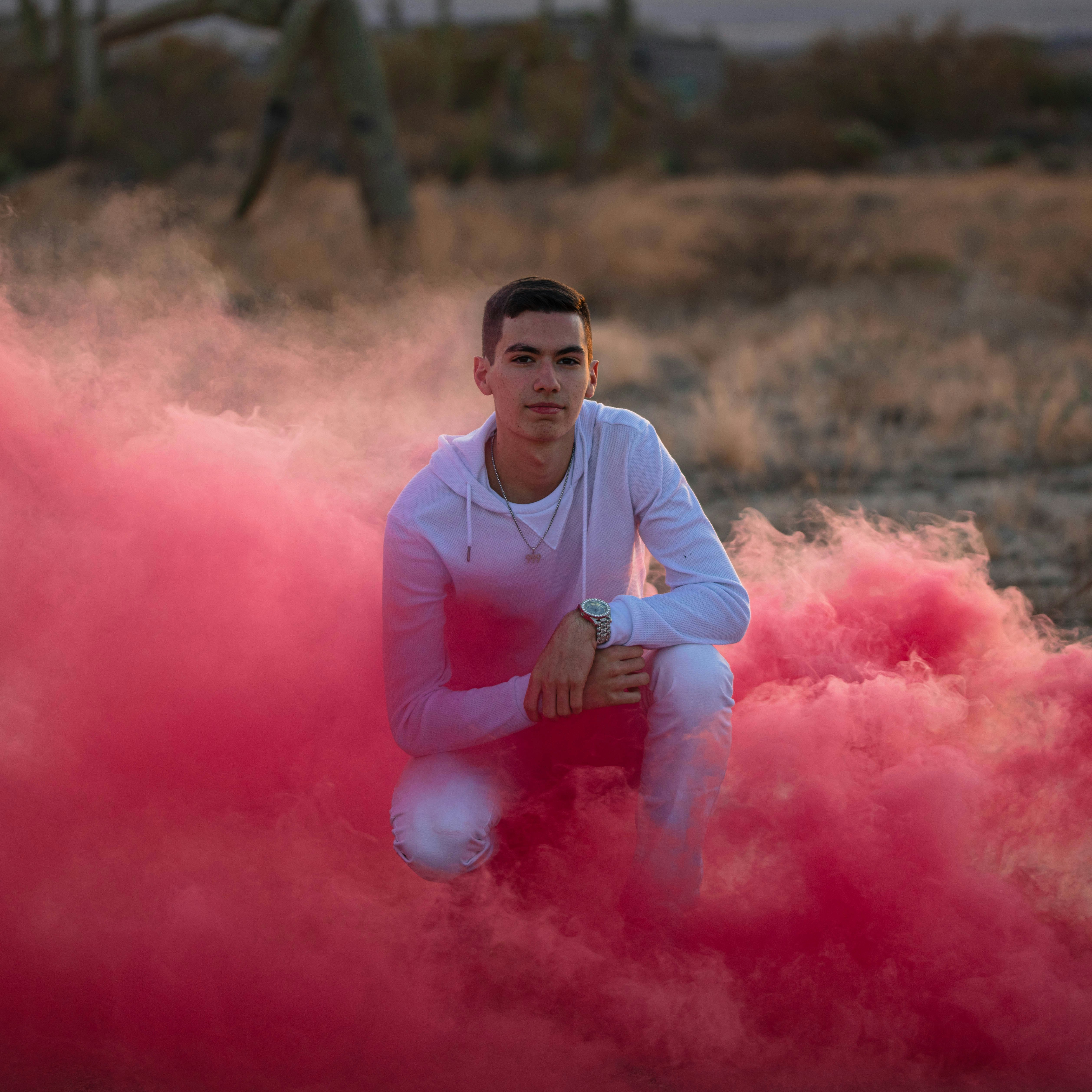 man in white crew neck t-shirt sitting on pink smoke